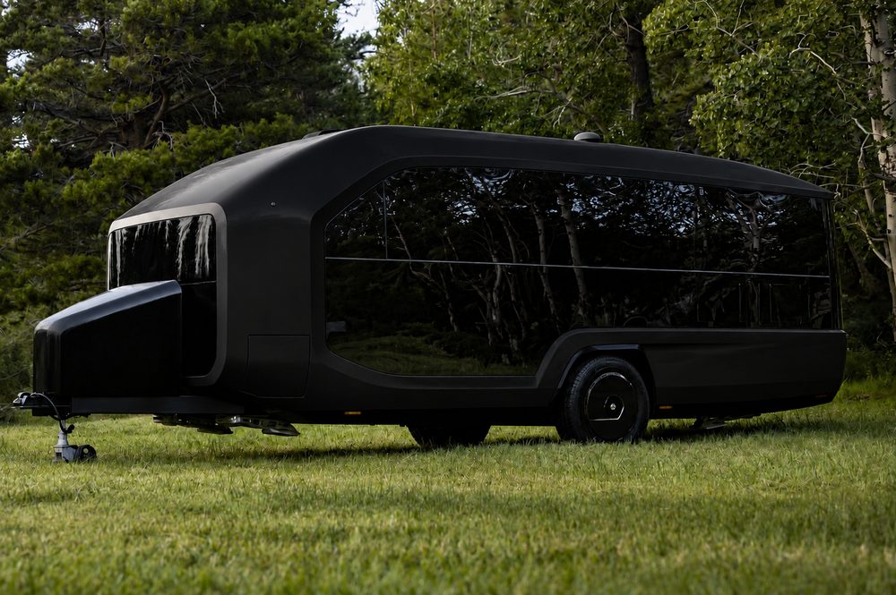 Flat matte black Pebble Flow concept parked on grass among aspens and pines
